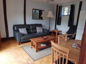 ein Wohnzimmer mit einem schwarzen Sofa und einem Tisch in der Unterkunft Low Farm Cottages in Woodbridge