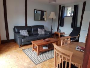 a living room with a black couch and a table at Low Farm Cottages in Woodbridge