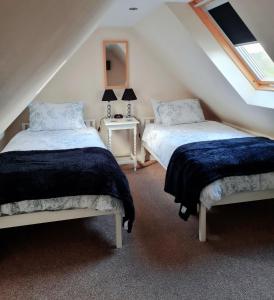 2 camas num quarto no sótão com uma janela em Hebridean Town House em Stornoway