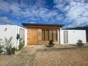 a small house with a wooden door in a yard at Littlebeads in Chichester