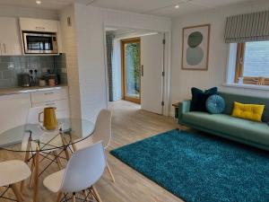 Littlebeads في شيشستر: غرفة معيشة مع أريكة خضراء وطاولة زجاجية