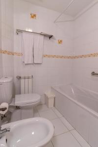 e bagno bianco con servizi igienici, vasca e lavandino. di Casa da Levada a Termas de São Pedro do Sul Altre 29 foto