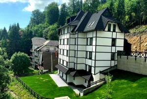 a large white house with a black roof at Vila Irina Kopaonik - Apartman IN in Kopaonik