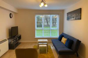 a living room with a blue couch and a window at Marie’s Serviced Apartment E, 2bedroom City Stay with River View in Bedford