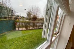 a window with a view of a yard with green grass at Marie’s Serviced Apartment E, 2bedroom City Stay with River View in Bedford