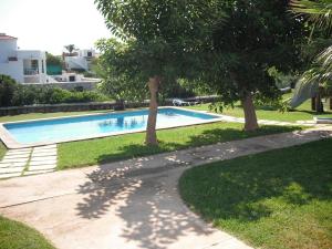 uma piscina com árvores ao lado de uma casa em Apartamento Calan Forcat en Ciutadella de Menorca em Ciutadella