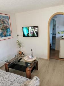 a living room with a glass table and a tv on the wall at Bungalow bei Warnemünde in Elmenhorst