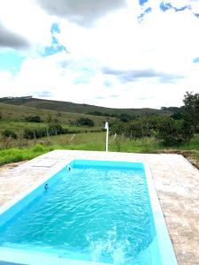 une piscine avec de l'eau bleue dans une cour dans l'établissement Sítio Tapera em Ibitipoca - MG, com Wi-Fi, à Conceição da Ibitipoca