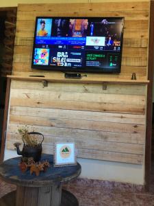 - une télévision sur un mur en bois avec une table dans l'établissement Sítio Tapera em Ibitipoca - MG, com Wi-Fi, à Conceição da Ibitipoca