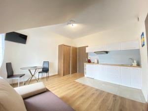 a kitchen with white cabinets and a table with chairs at Dom Nad Brennica Pokoje i Apartamenty in Brenna