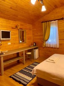 Schlafzimmer mit einem Bett und einem Schreibtisch mit einem TV in der Unterkunft Safir Pansiyon in Cıralı