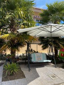 a white umbrella and a bench and palm trees at Cozy home in Pertegada