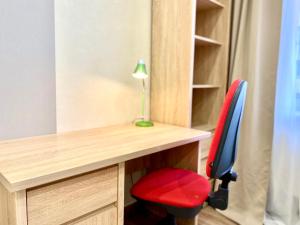 a desk with a red chair and a lamp at ApartPoltava Cучасні 2-кімн апартаменти з великою кутовою ванною ЦЕНТР МІСТА in Poltava