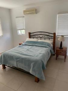 a bedroom with a bed with a blue blanket on it at Los Corozos apartment M2, Guavaberry Golf & Country Club in Juan Dolio
