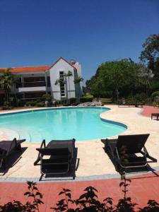 璜多里奧的住宿－Los Corozos apartment M2, Guavaberry Golf & Country Club，一座带椅子的大型游泳池和一座建筑