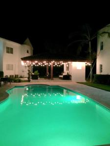 una piscina frente a una casa por la noche en Los Corozos apartment M2, Guavaberry Golf & Country Club, en Juan Dolio
