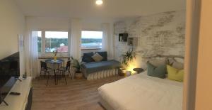 ein Schlafzimmer mit einem Bett, einem Sofa und einem Fenster in der Unterkunft Liebevoll renoviertes Apartment mit Panoramablick in Friedrichshafen