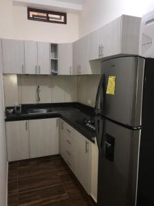 a kitchen with a black refrigerator and white cabinets at CRUCITALIA suite x 4 in Crucita