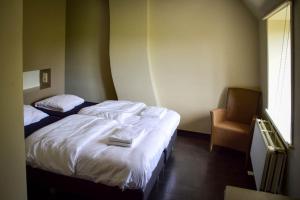 una habitación de hotel con una cama y una silla en Doeselie deux, en Ronse