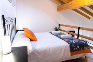 1 dormitorio con cama blanca y almohada naranja en Apartamentos Las Secuoyas, en Ayuela