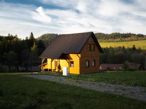 une petite maison jaune dans un champ d'herbe dans l'établissement Chata Karamelka, à Dolní Moravice