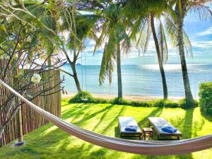 a hammock on a beach with palm trees and the ocean at Nibbana Bungalows in Hinkong