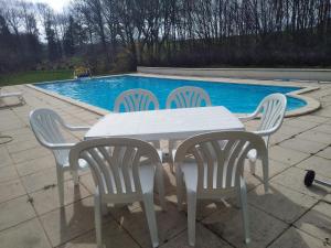 a white table and chairs next to a swimming pool at Charming Country Estate in Dournazac