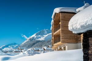un bâtiment recouvert de neige avec une montagne en arrière-plan dans l'établissement Vetta Alpine Relax, à Livigno
