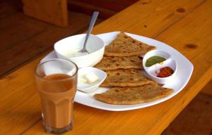 a plate of food with bread and a drink on a table at HOTEL SATYA in Dehradun
