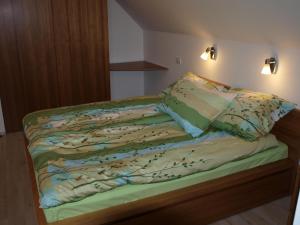 Una cama con sábanas verdes y almohadas. en Apartment Knap en Cerknica
