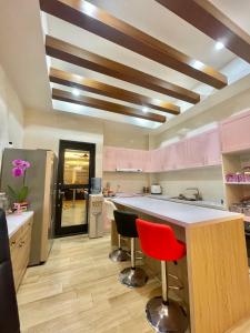 une cuisine avec des placards roses et un comptoir avec des chaises rouges dans l'établissement Happy Wind Homestay, à Magong