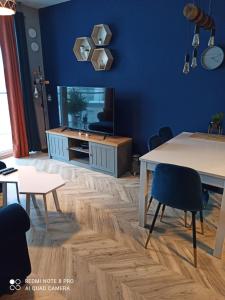 - un salon avec des murs bleus, une table et des chaises dans l'établissement Nowoczesny Apartament przy Manufakturze z parkingiem podziemnym i klimatyzacją, à Łódź