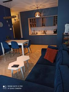 uma sala de estar com um sofá azul e uma mesa em Nowoczesny Apartament przy Manufakturze z parkingiem podziemnym i klimatyzacją em Lódź