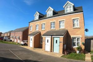 a large brick building with white doors and a parking lot at Cosy townhouse near Kidwelly in Kidwelly