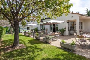 a patio with tables and chairs and a tree at Campanile NATURE - Montpellier Sud in Montpellier