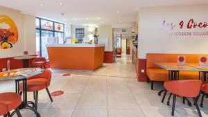 ein Restaurant mit orangefarbenen Stühlen, Tischen und einer Theke in der Unterkunft Hotel Ours Blanc - Centre in Toulouse