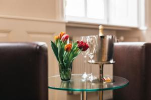 einen Glastisch mit einer Vase aus Blumen und Weingläsern in der Unterkunft Amtshaus Freinsheim in Freinsheim
