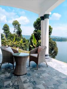 a patio with chairs and a table and water at Villa Bunyonyi in Kabale