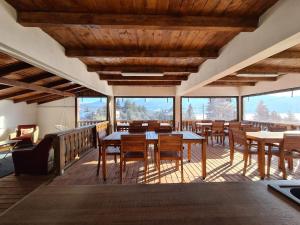 a dining room with tables and chairs and windows at Pensiunea Encian in Colibiţa