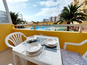 une table blanche avec des assiettes et des verres à vin sur un balcon dans l'établissement Sunny Cozy Nice Apartment LosCristianos WiFi,Pool, à Los Cristianos