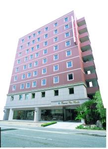 un grand bâtiment rouge avec une rue en face dans l'établissement Tourist Inn Kochi, à Kōchi