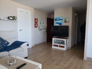 a living room with a couch and a flat screen tv at Apartamento Urbanova in Arenales del Sol