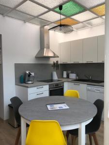 a kitchen with a table and some yellow chairs at La maison du bonheur proche plage composée de 2 appartement et d'une belle terrasse in Étaples