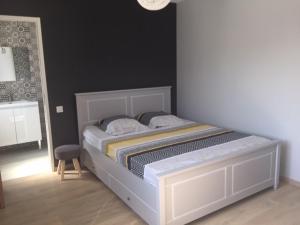 un letto bianco in una stanza con sedia di La maison du bonheur proche plage composée de 2 appartement et d'une belle terrasse a Étaples