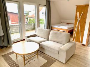 ein Wohnzimmer mit einem Sofa, einem Tisch und einem Bett in der Unterkunft Vineta Ferienwohnungen in Mölschow