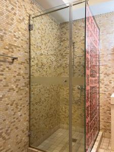 una doccia in vetro in un bagno con parete di mattoni di Hotel Mangalemi a Berat