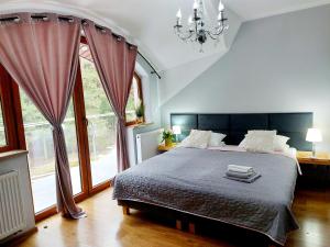 a bedroom with a bed and a large window at Saskia Dwór & Spa Willa z basenem in Podmacharce