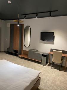 a bedroom with a bed and a desk and a tv at Astrum Palace in Mažeikiai