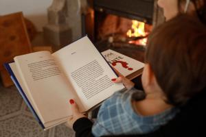 a woman reading a book in front of a fireplace at B&B Il Tritone in Laviano