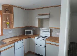 a kitchen with white appliances and a microwave at Four waves in Thurso